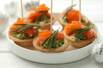 Tasty canapes and Christmas decor on white wooden table, closeup