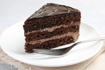 Piece of delicious chocolate cake and fork on table, closeup