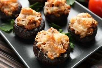 Delicious stuffed mushrooms with parsley on wooden table, closeup