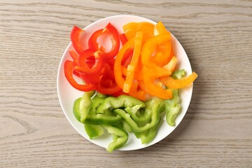 Slices of fresh colorful bell peppers on wooden table, top view