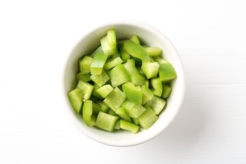 Pieces of fresh green bell pepper in bowl on white wooden table, top view