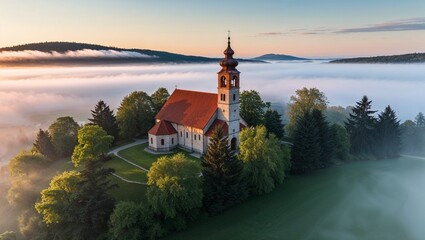 Fototapeta premium Peaceful church enveloped in morning fog and lush trees.