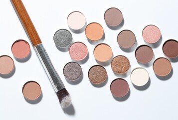 Beautiful eyeshadow refill pans and brush on white background, flat lay