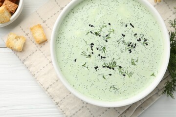 Tasty cucumber soup, croutons and ingredients on white wooden table, flat lay