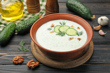 Tasty cucumber soup with dill, walnuts and ingredients on wooden table, closeup