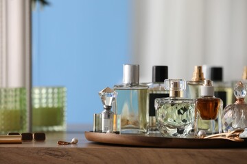 Bottles of different perfumes and accessories on wooden table, closeup. Space for text