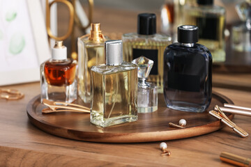 Bottles of different perfumes and accessories on wooden table, closeup