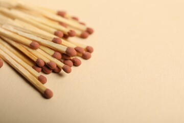 Matches with brown heads on beige background, closeup. Space for text