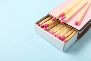 Matches and box on light blue background, closeup. Space for text