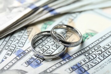 Two silver wedding rings on dollar banknotes, closeup