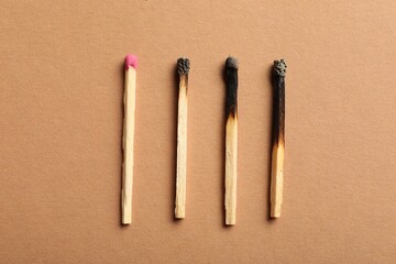 Burnt and whole matches on beige background, flat lay