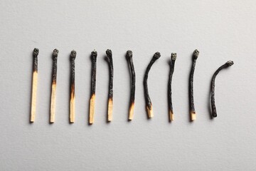 Burnt matches on grey background, flat lay