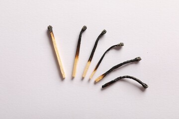 Burnt matches on light grey background, flat lay
