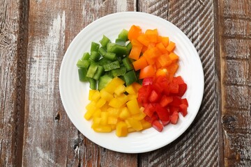 Cut colorful bell peppers on wooden table, top view