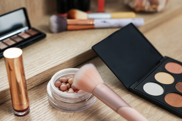 Different makeup products and brush on vanity indoors, closeup