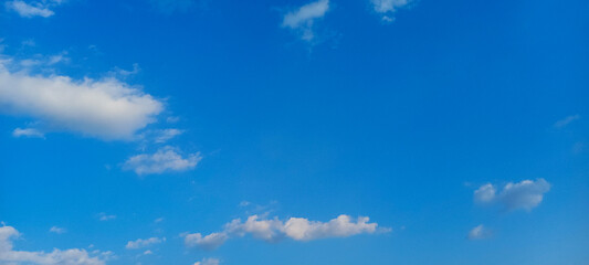 Obraz premium Vibrant blue sky with scattered white clouds. A peaceful and clear daytime skyscape.