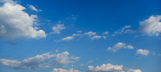Bright blue sky with scattered fluffy white clouds.