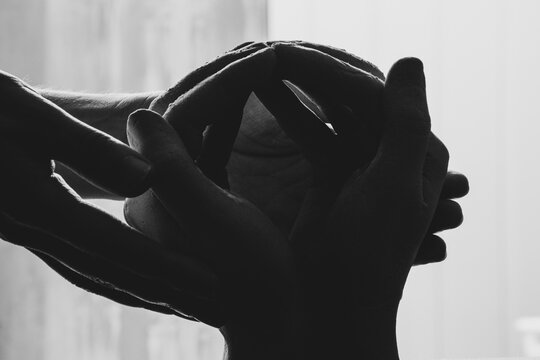 Female hands holding hands cast from plaster in the dark