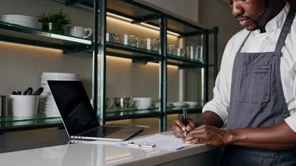 Professional chef reviewing recipe on clipboard in modern kitchen