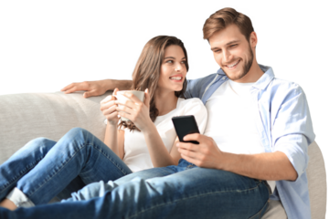 Young couple watching online content in a smart phone sitting on a sofa on a transparent background