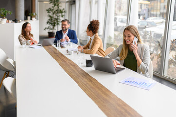 Businesswoman talking over smart phone and professionals discussing strategies and planning project...