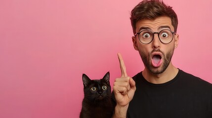 Shocked impressed guy has trendy haircut, bristle, wears round glasses, black shirt, stands near his favourite pet, indicates with index finger at copy space on right side, shows something incredible