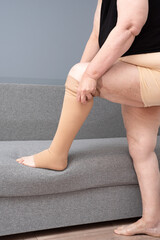 Anonymous woman removes medical compression stockings from her leg. Stockings for maintaining the tone of veins and valves. Prevention of thrombosis