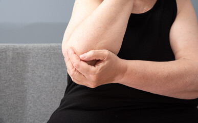 Adult woman with pain in arm holding herself. Self-care, preventive medicine