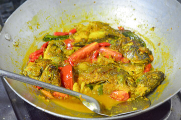 Fish curry that is being cooked using thick and spicy coconut milk
