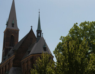 Fototapeta premium An elegant church adorned with beautiful spires, perfectly set against a bright blue sky and surrounded by lush greenery
