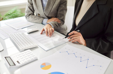 Close-up of business colleagues working with financial documents, diagrams, and graphs during...