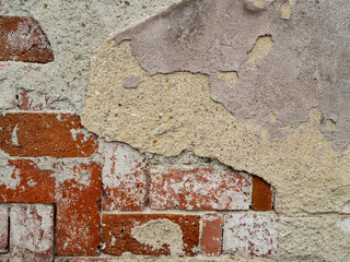 Close-up of an old brick wall partially covered with cracked and peeling plaster. Rustic texture...