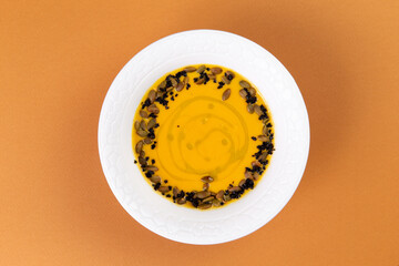 Pumpkin soup garnished with seeds in a plate.
