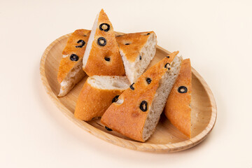 Ciabatta with olives on a wooden plate.