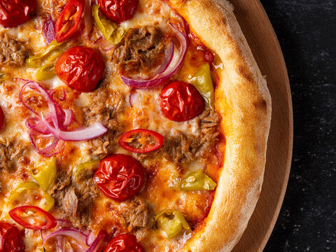 Spicy pizza topped with pulled beef, cherry tomatoes, red onions, yellow peppers, red chili slices