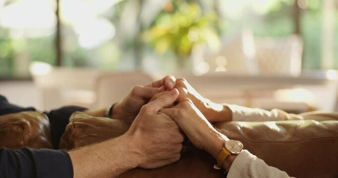 Couple, sofa and holding hands with empathy for trust, commitment or comfort in marriage at home. Closeup, people or support with touch, understanding or safety for sympathy, care or love at house