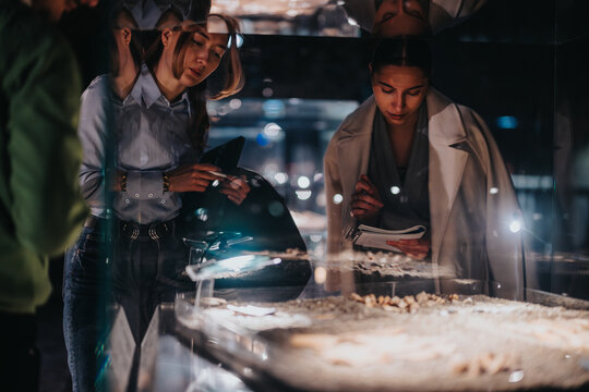 Visitors at a museum exhibit examine displays closely, conveying an atmosphere of curiosity and discovery.