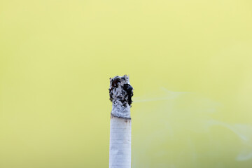 Macro Shot of a Burning Cigarette Against a Blurred Yellow Background