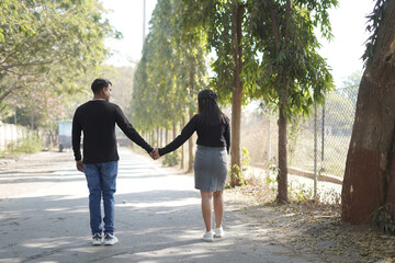 Fototapeta premium A young couple lovingly embracing while standing on a quiet, tree-lined path on a sunny day