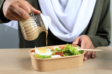 Female hand Pouring Sesame Dressing to the Fresh Salad