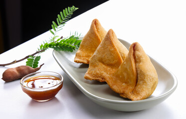 Most popular snacks called Samosa with Imali sauce serve in plate isolated on white background 