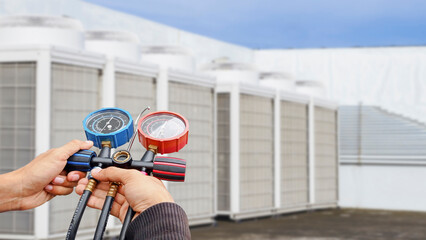 Air repair mechanic using measuring equipment for filling industrial factory air conditioners.	