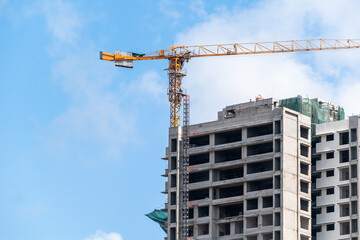 A crane is lifting materials at a construction site for a high-rise building in an urban environment.