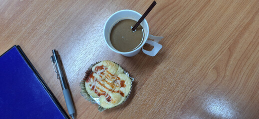 Coffee in a paper cup and bread, books, pens in the office