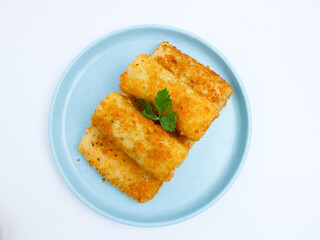 Golden crispy risol mayo stacked on a light blue plate, isolated on a white background