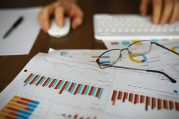Business Analyst Working on Financial Reports with Charts and Graphs on Desk