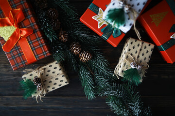 Christmas Gift Boxes with Pine Cones and Evergreen Branches on Dark Wooden Background