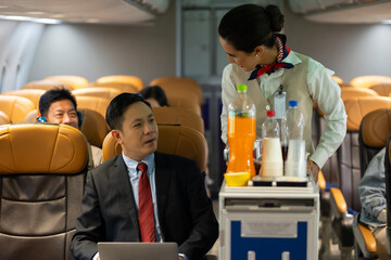 Business trip vacation and travel concept. Asian business Man travelling by plane and working on...