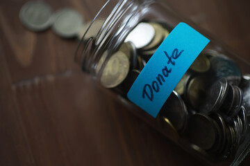 Glass Jar Filled with Coins for Donations on Wooden Table