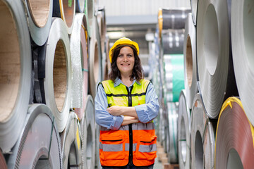 portrait of smilling engineer worker woman in safety vest and helmet standing crossed arms between...